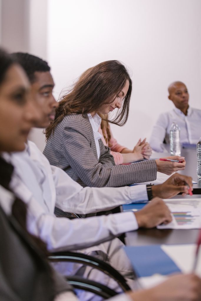 A diverse group of professionals engaged in a focused and attentive business meeting in a conference room.